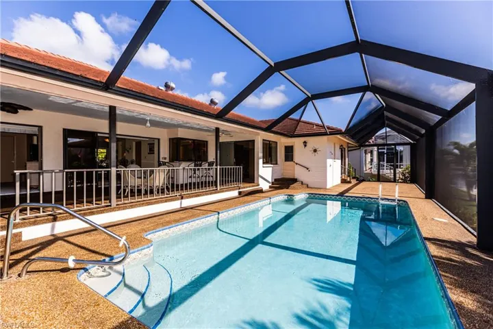View of swimming pool featuring ceiling fan, glass enclosure, and a patio