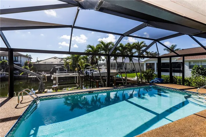 View of swimming pool with a water view, a lanai, and a boat dock