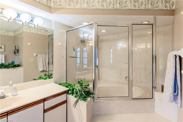 Bathroom featuring vanity and shower / bath combination with glass door