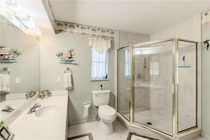 Bathroom featuring toilet, vanity, tile patterned floors, and walk in shower