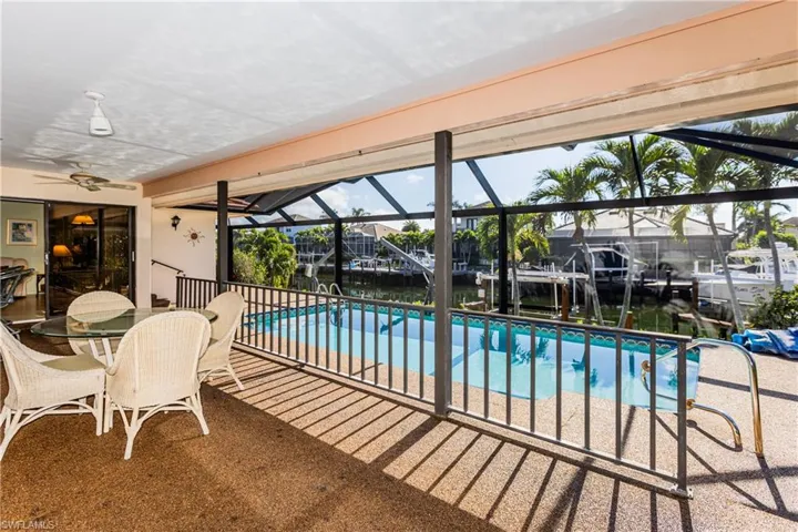 View of pool featuring ceiling fan, a water view, glass enclosure, and a patio area