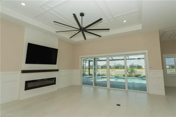 Unfurnished living room with wainscoted wall, custom fireplace, a decorative ceiling, ceiling fan, recessed lighting, and views of pool/spa