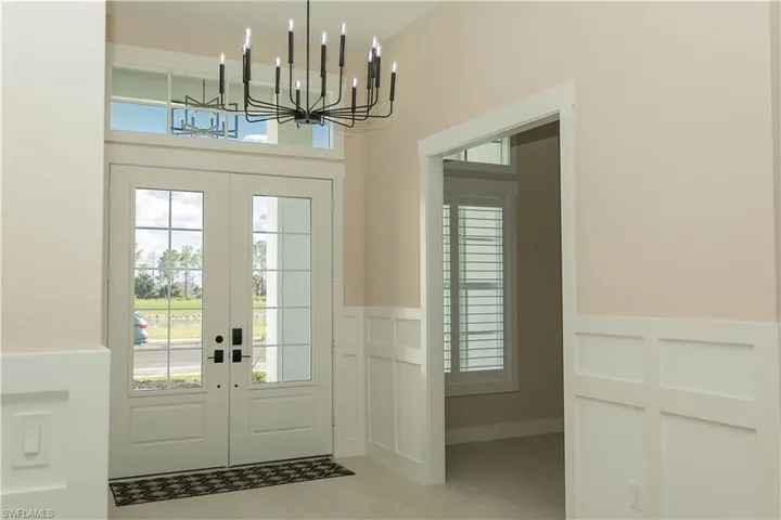 Doorway with plenty of natural light, wainscoted wall, chandelier, french doors