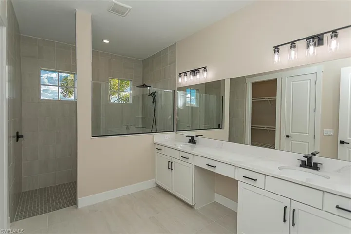 Master bath featuring double vanity, a walk in shower, a spacious custom closet, and recessed lighting, featuring matte black fixtures, floor to ceiling tile in shower