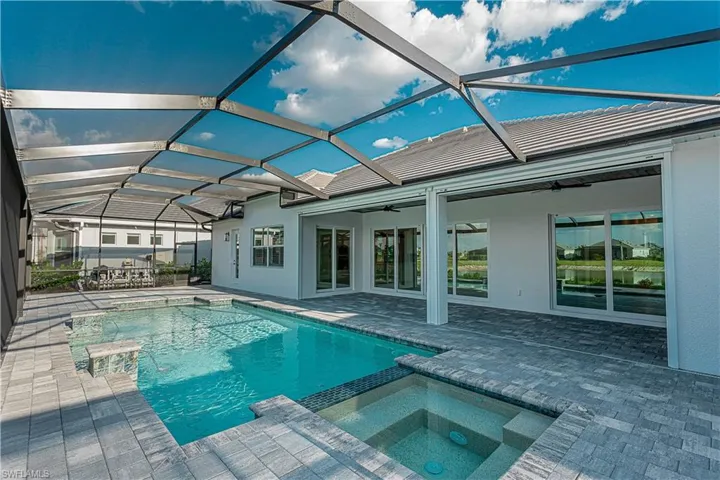 Salt water gas heated concrete pool / spa under screened lanai with sealed pavers and custom outdoor kitchen, views of lake/golf course