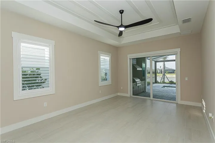 Owner's suite with a ceiling fan, custom glass door privacy screen, plantation shutters, ceiling fan under decorative ceiling.