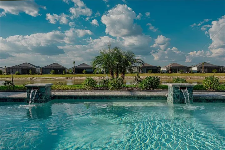 Salt water gas heated concrete pool / spa under screened lanai with sealed pavers and custom outdoor kitchen, views of lake/golf course