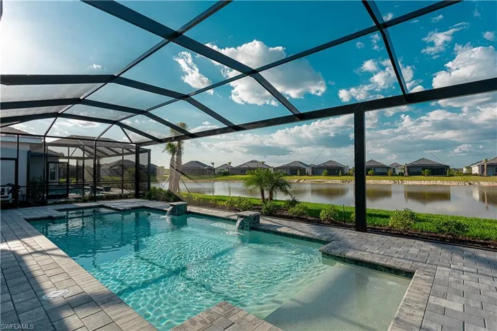 Salt water gas heated concrete pool / spa under screened lanai with sealed pavers and custom outdoor kitchen, views of lake/golf course