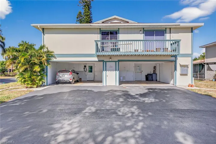 View of front of house featuring a carport, a balcony, and asphalt driveway