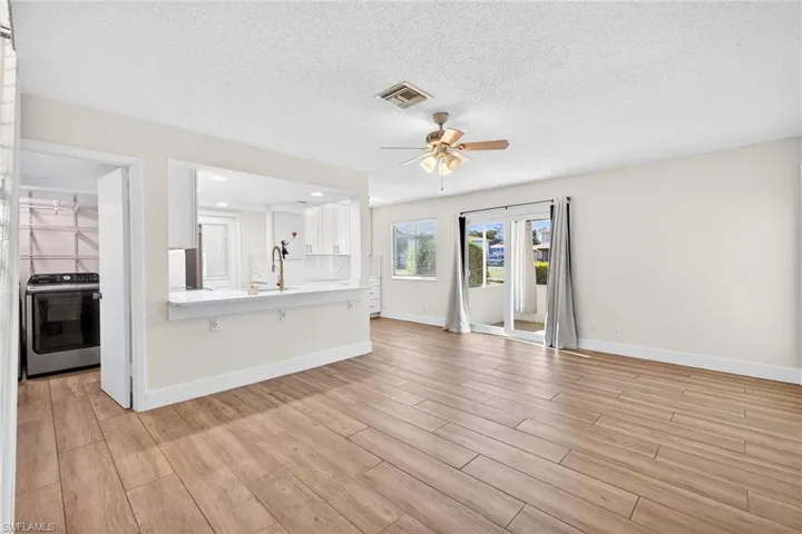Unfurnished living room featuring washer / clothes dryer, light wood-style flooring, a textured ceiling, ceiling fan, and recessed lighting