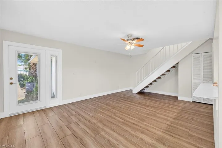 Unfurnished living room with light wood-style flooring, stairway, and ceiling fan