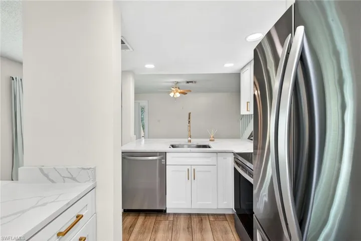 Kitchen featuring stainless steel appliances, light stone counters, white cabinetry, and recessed lighting