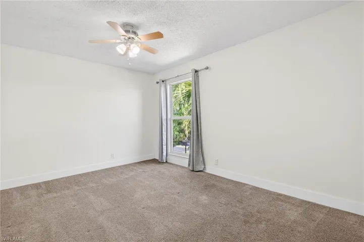 Empty room featuring carpet floors, a textured ceiling, and ceiling fan