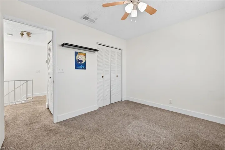 Unfurnished bedroom featuring a textured ceiling, carpet flooring, ceiling fan, and a closet