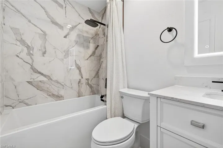 Full bathroom with shower / tub combo with curtain and vanity