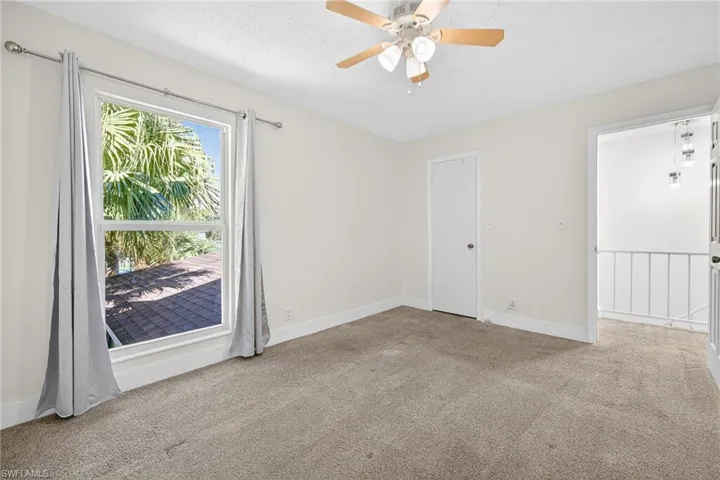 Spare room featuring light carpet, a textured ceiling, and ceiling fan