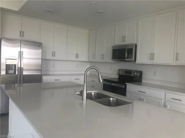 Kitchen with sink, an island with sink, stainless steel appliances, and white cabinetry