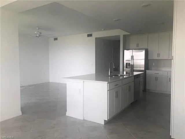 Kitchen with dishwasher, ceiling fan, a kitchen island with sink, sink, and light tile floors