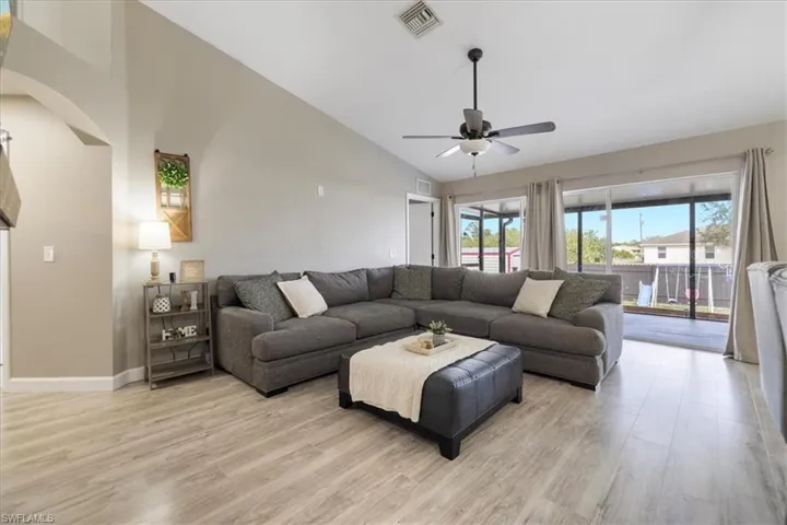 Living room featuring high vaulted ceiling, light hardwood / wood-style floors, and ceiling fan