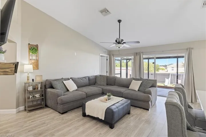 Living room with ceiling fan, high vaulted ceiling, and light hardwood / wood-style flooring