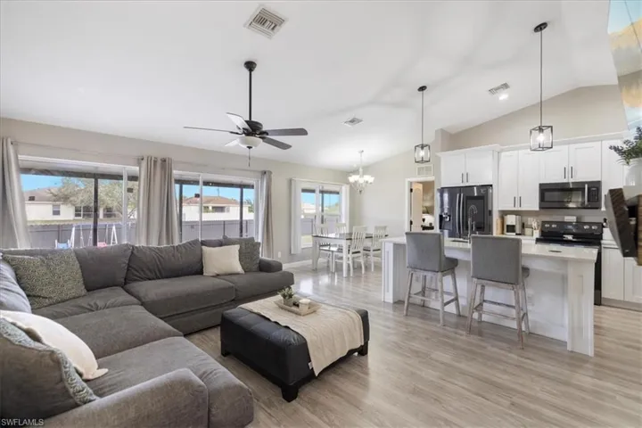 Living room featuring vaulted ceiling, ceiling fan, and light hardwood / wood-style flooring