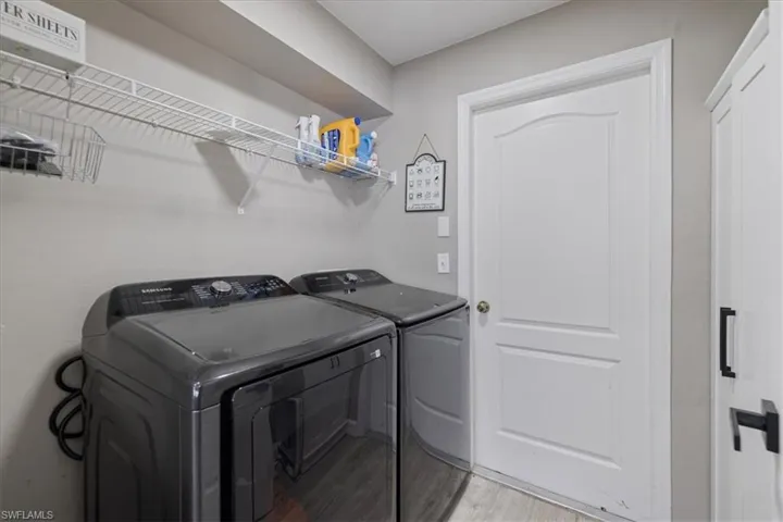 Clothes washing area with independent washer and dryer and light wood-type flooring
