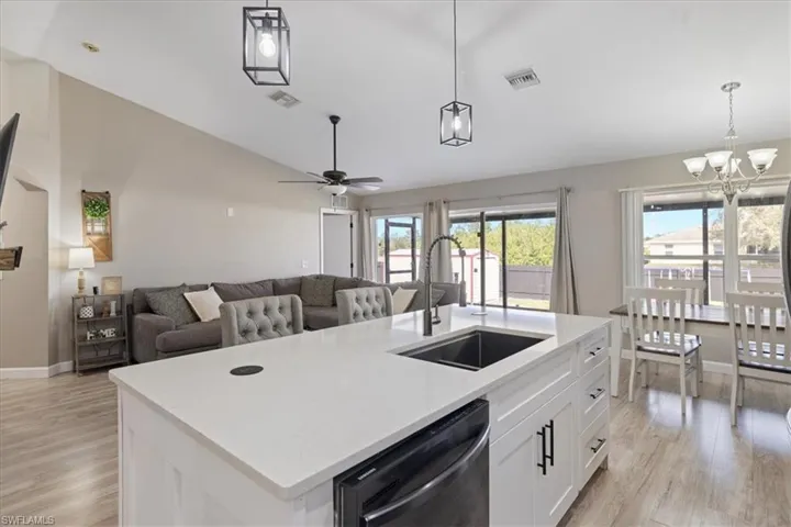 Kitchen featuring a kitchen island with sink, sink, hanging light fixtures, and dishwasher