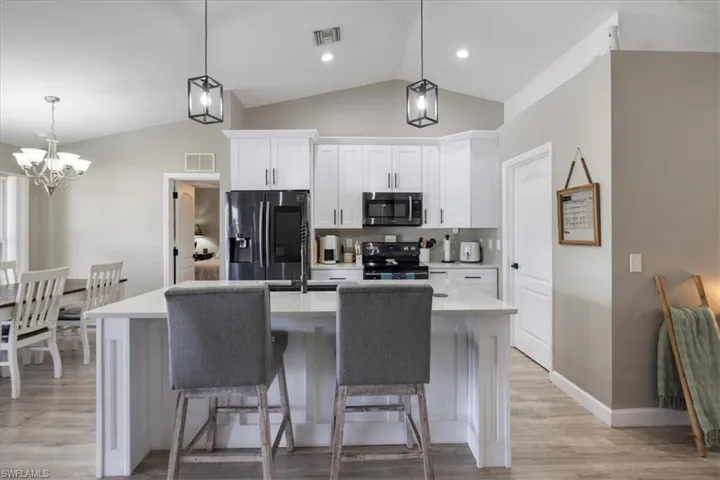Kitchen with white cabinetry, appliances with stainless steel finishes, and a center island with sink