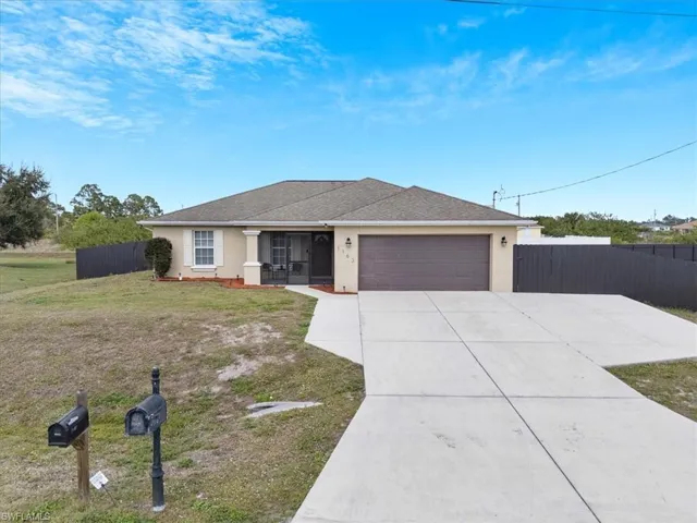 Ranch-style home with a garage, a front yard, and covered porch