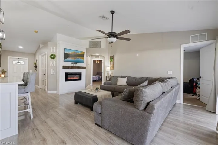 Living room featuring vaulted ceiling, ceiling fan, and light hardwood / wood-style floors