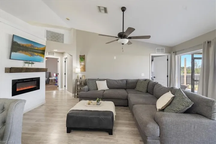 Living room with vaulted ceiling, light hardwood / wood-style floors, and ceiling fan