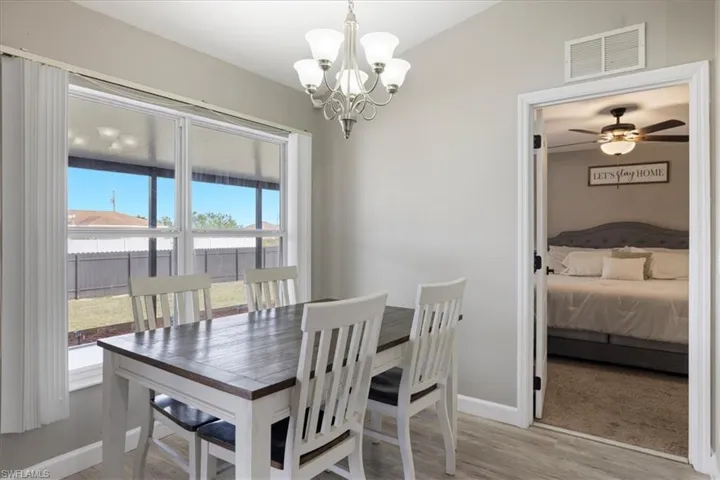 Dining space featuring ceiling fan with notable chandelier and light wood-type flooring