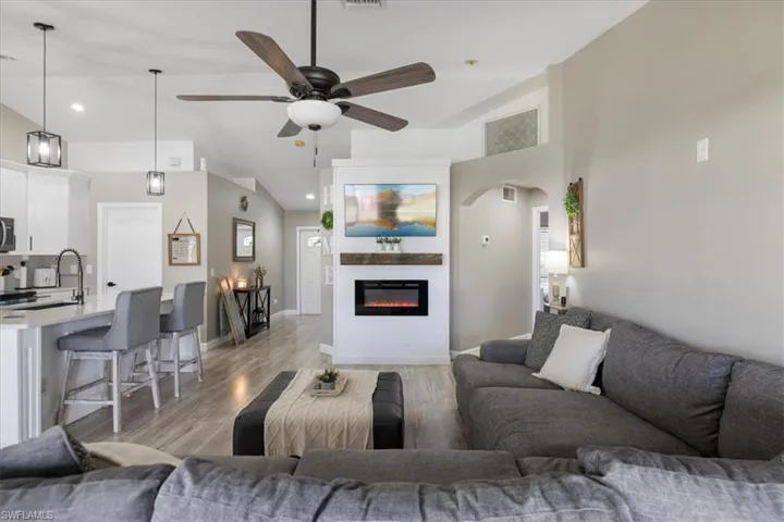 Living room with ceiling fan, high vaulted ceiling, sink, and light hardwood / wood-style floors