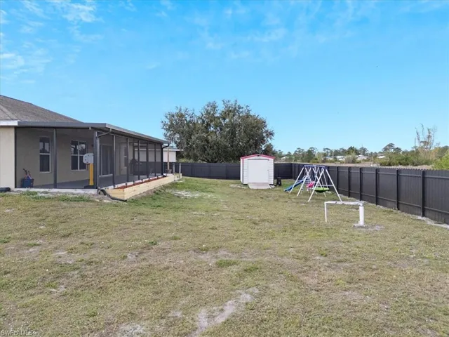 View of yard with a sunroom, a playground, and a shed
