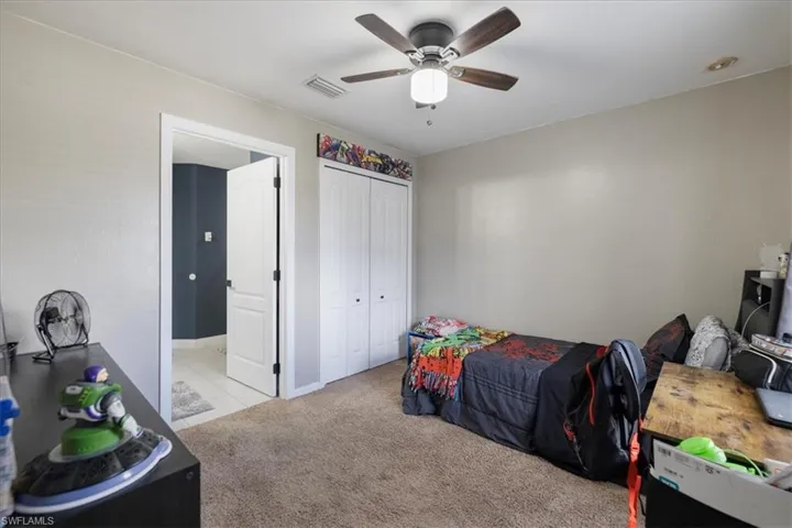 Carpeted bedroom featuring a closet and ceiling fan