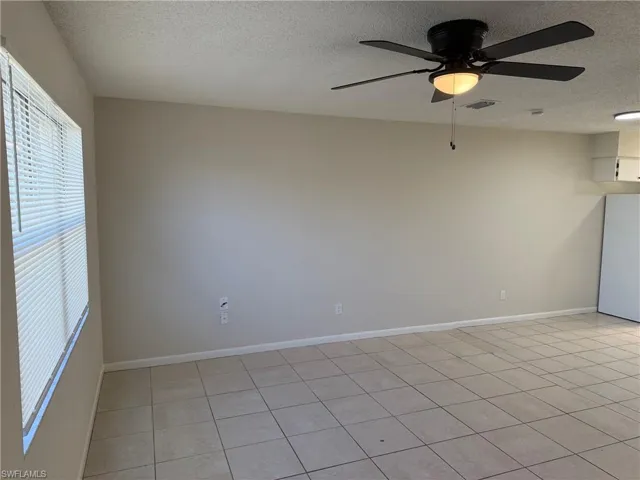Unfurnished room featuring a ceiling fan, a textured ceiling, and light tile patterned flooring