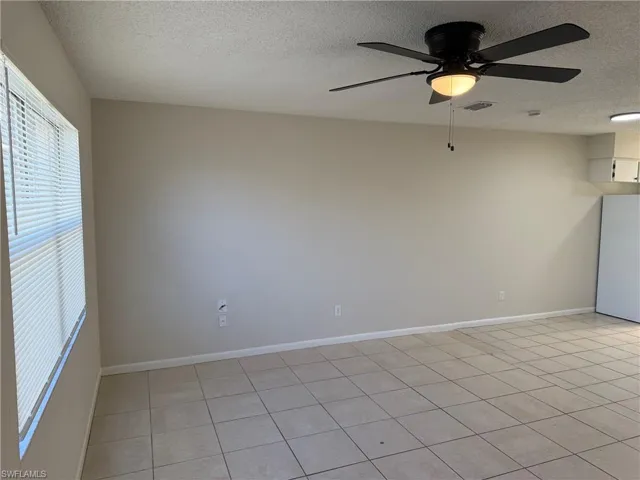 Empty room featuring ceiling fan, a textured ceiling, and light tile patterned floors