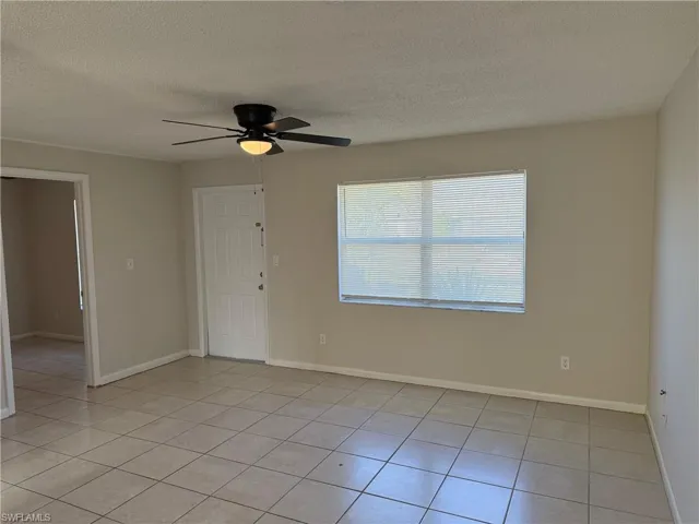 Unfurnished room with a textured ceiling, a ceiling fan, and light tile patterned floors