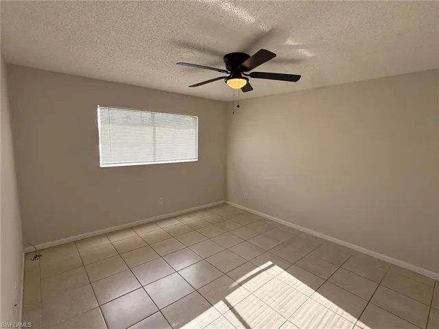 Unfurnished room with a textured ceiling, a ceiling fan, and light tile patterned flooring