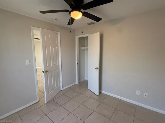 Unfurnished bedroom with a textured ceiling, ceiling fan, light tile patterned floors, and a closet