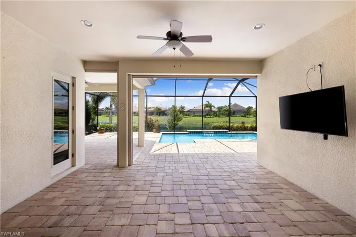View of swimming pool with glass enclosure, a patio area, and ceiling fan