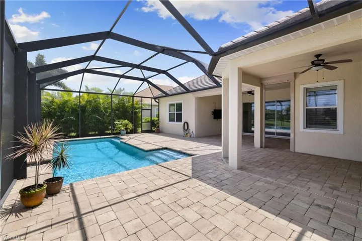 View of swimming pool with a patio, ceiling fan, and glass enclosure