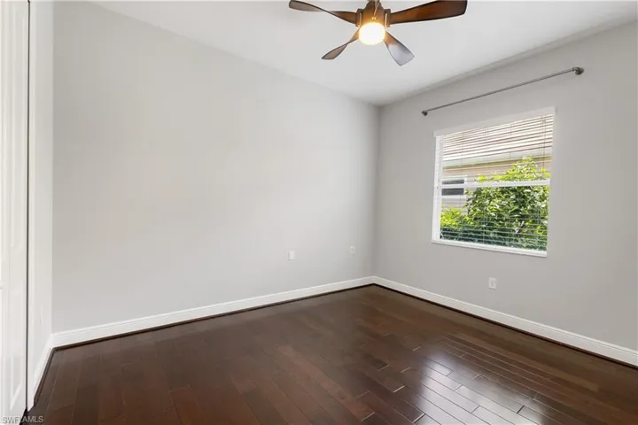 Spare bed room with ceiling fan and wood-type flooring.