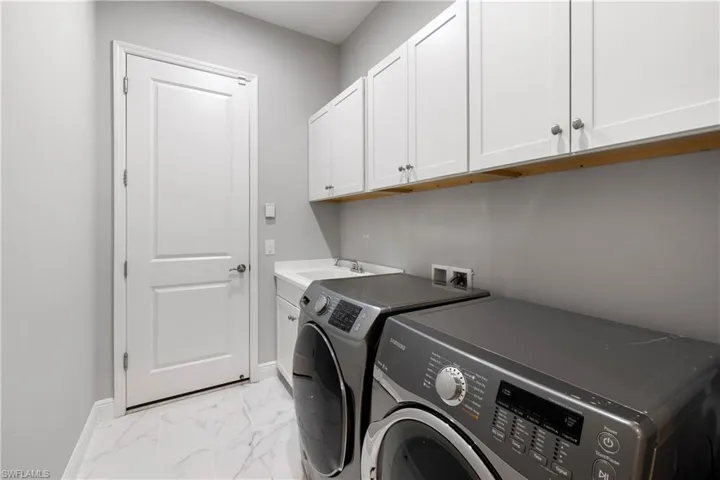 Laundry with sink featuring light tile patterned flooring, washer and clothes dryer, sink, and cabinets
