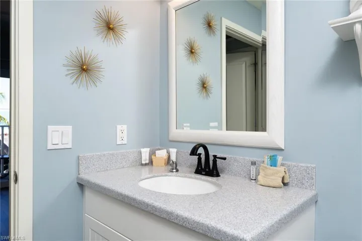 Bathroom vanity featuring a white cabinet, speckled countertop, and an undermount sink with a matte black faucet