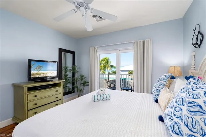 Sliding glass doors opening to an outdoor area, light blue wall paint, a white ceiling fan, and wood-finish flooring