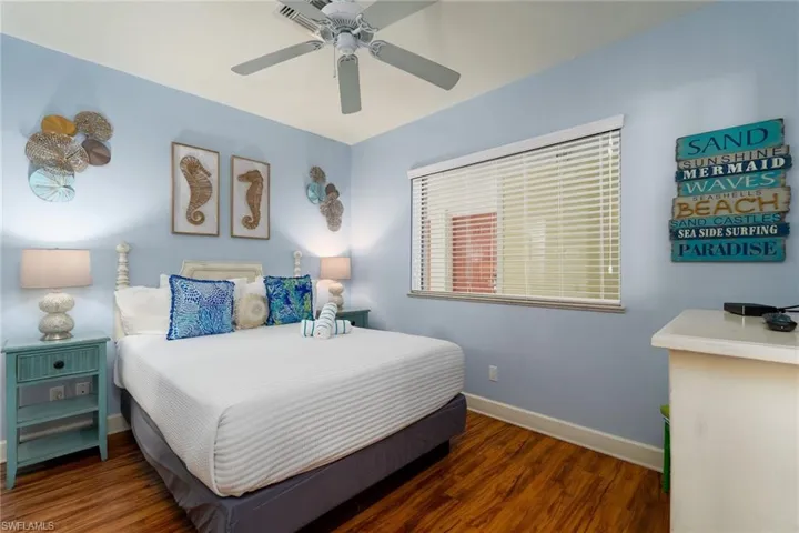 Bedroom featuring wood-finish flooring, a ceiling fan, and a window with horizontal blinds