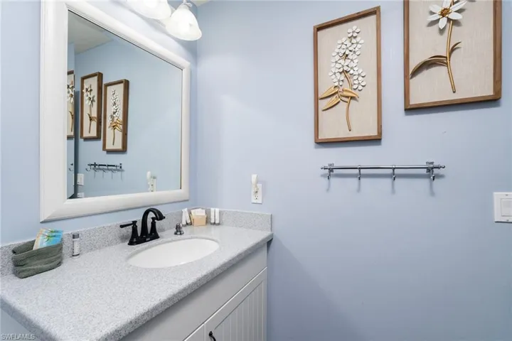 Bathroom vanity featuring a speckled countertop, undermount sink, and matte black faucet