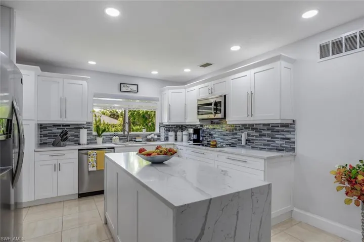 Kitchen featuring stainless steel appliances, white cabinetry, tasteful backsplash, and light tile floors