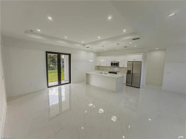 Kitchen with open floor plan, a tray ceiling, appliances with stainless steel finishes, white cabinets, and recessed lighting